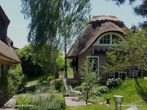 Kryta strzechą drewutnia w ogrodzie, połączona z domkiem dla dzieci - kalenica angielska, tkana łupkami leszczynowymi