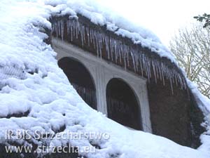 Strzecha na dachu z trzciny - Wildschire w Anglii. Sople lodu okalające okno w dachu krytym strzechą